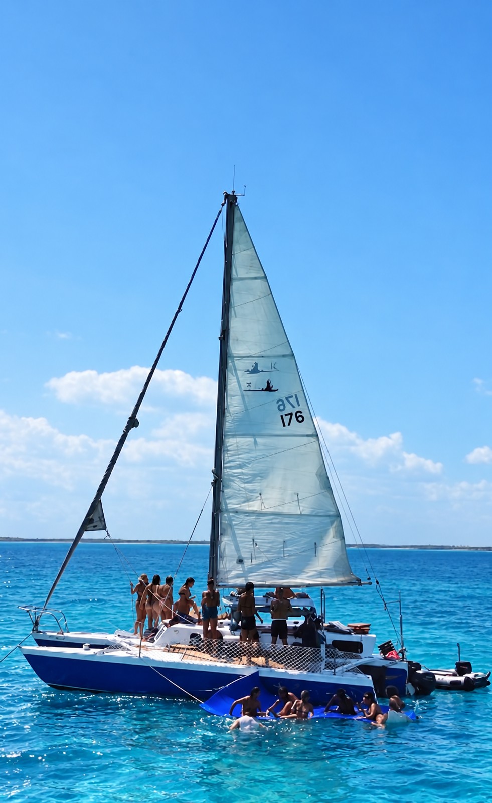 Our trimaran with guests on its open deck in blue waters around Holbox